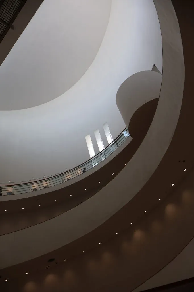 Curved white balconies winding upward through a tall building interior.